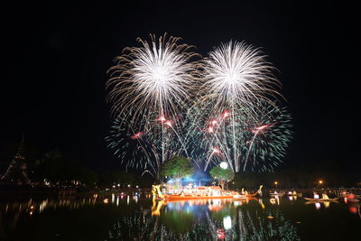 Low angle view of firework display over river at night