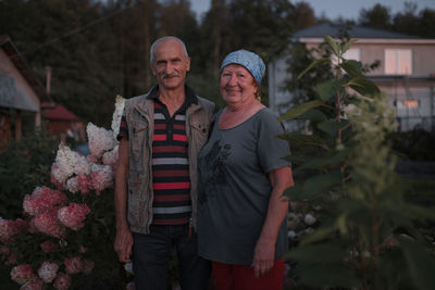 Portrait of smiling man and woman standing by plants