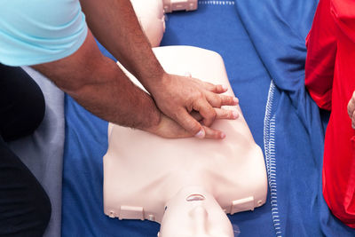 Midsection of instructor teaching paramedic while performing cpr on dummy