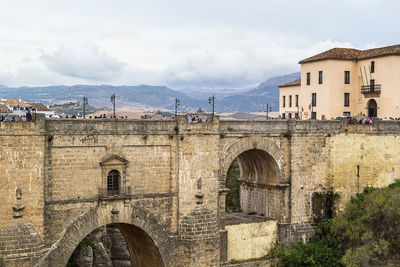 Arch bridge in city against sky