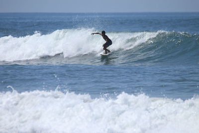 Man surfing in sea against sky