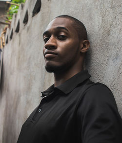 Portrait of young man standing by wall