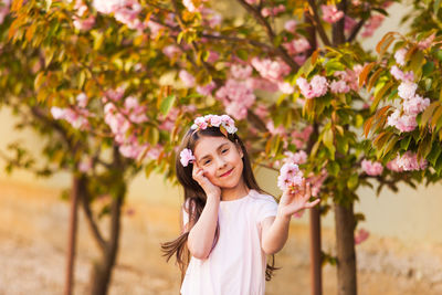 Portrait of smiling girl standing against flowering tree