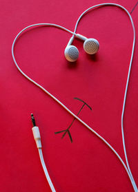 Heart shape made from headphones on red table