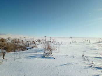 Scenic view of snow covered land against clear blue sky