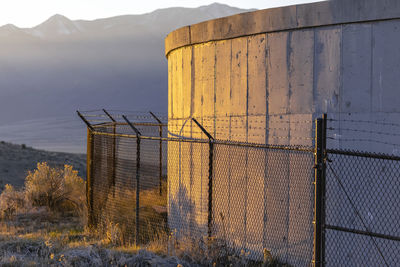 Metal fence by factory against sky