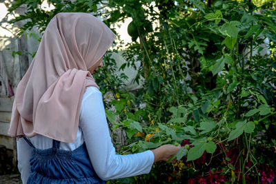 Side view of woman with umbrella against plants