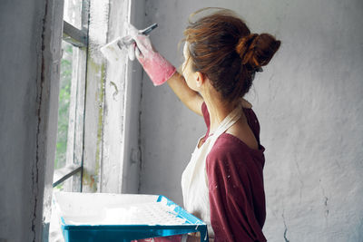 Rear view of woman standing against wall