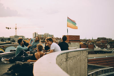 Friends enjoying rooftop party in city against sky
