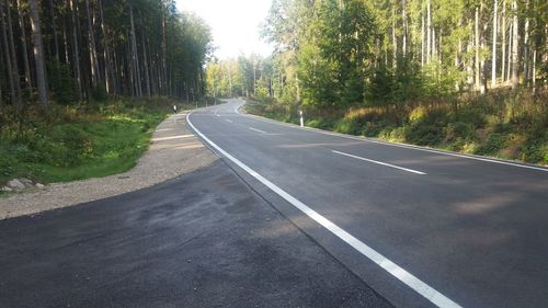 Empty road along trees in forest