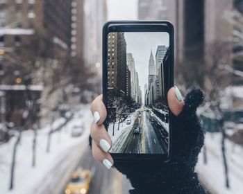 Close-up of woman photographing through smart phone in winter