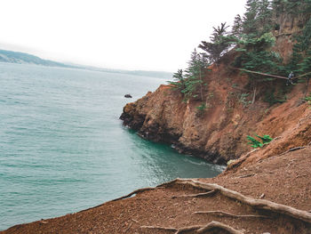 Scenic view of sea by cliff against sky