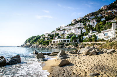 Low angle view of town on hill by sea against sky