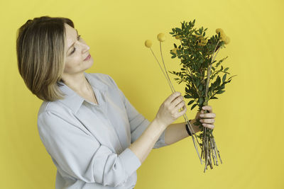 Young woman holding yellow flower