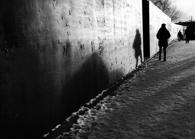 Rear view of silhouette man walking on footpath