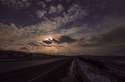 Country road against cloudy sky