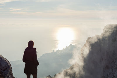 A young woman stands on a mountain watching the sunset. atmospheric evening view 