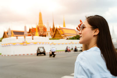 Side view of young woman at temple against sky