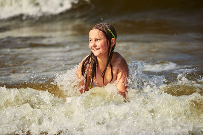 Portrait of young woman splashing water in lake