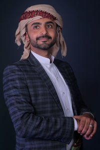Portrait of young man standing against black background