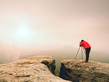 Man standing on rock at mountain against sky