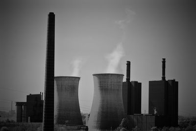 Smoke emitting from factory against sky