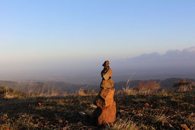 Stack of stones on landscape against sky