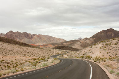 Scenic view of road by mountains against sky