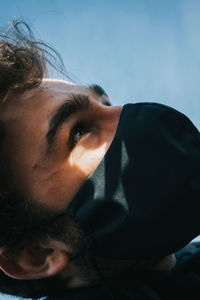 Close-up portrait of men looking up against the sky