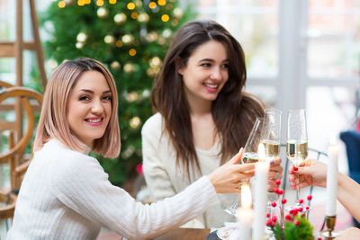 Portrait of smiling young woman toasting champagne against christmas tree