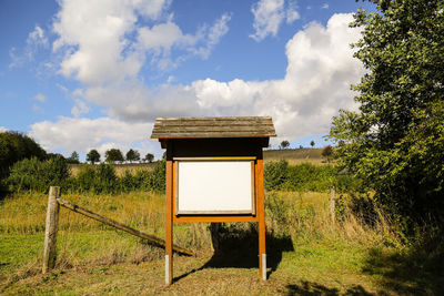Whiteboard on grassy field against sky