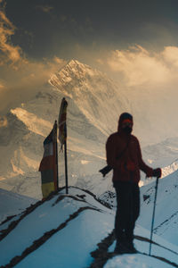 Rear view of man standing on snow covered landscape during sunset