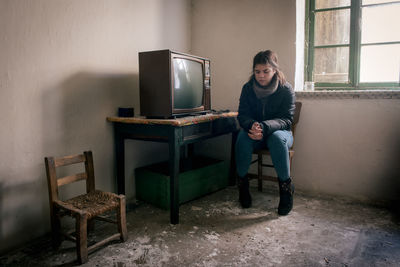 Young woman lonely in an abandoned ruined room with television. loneliness concept
