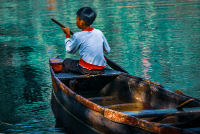 Boy sitting in boat against sea