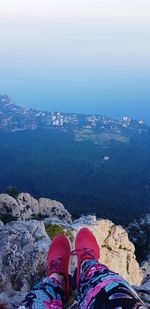 Low section of person on rock against sky