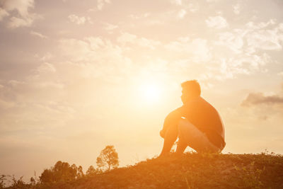 Silhouette man standing on field against sky during sunset