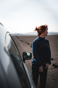 Young woman standing by car