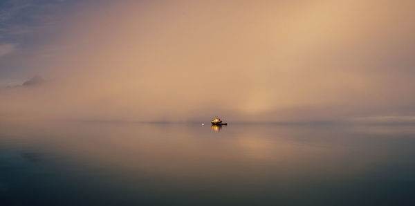 Silhouette boat in sea against sky during sunset