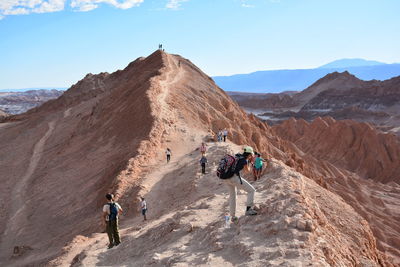 Rear view of woman walking on desert against mountain