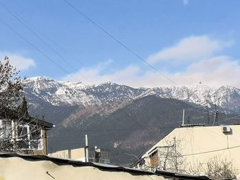 Snow covered houses by mountain against sky