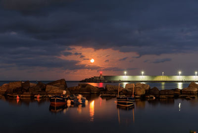 Illuminated bridge over river against sky at sunset