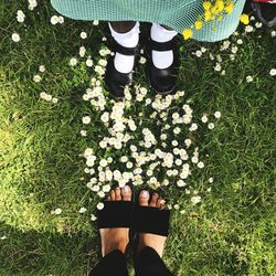 Low section of mother with daughter standing on grassy field at park