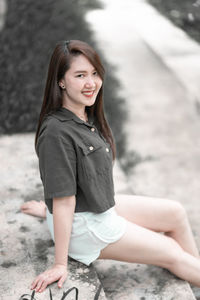 Portrait of young woman sitting on footpath