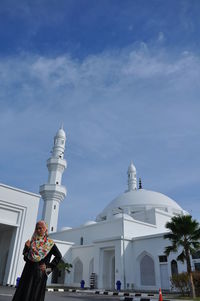 Teenage girl wearing traditional clothing standing against mosque during sunny day