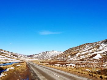 Empty road amidst snowcapped mountains at glenshee ski centre