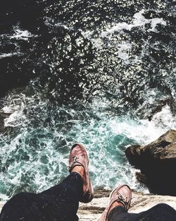 Low section of man standing on cliff by sea