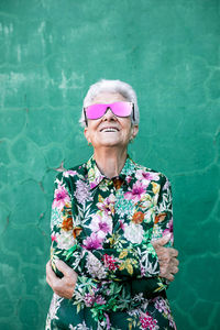 Portrait of smiling woman standing against wall