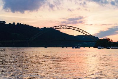 Bridge over river against sky at sunset