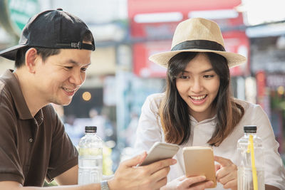 Smiling people using smart phones while sitting in cafe