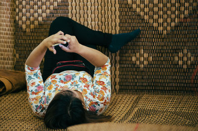 Full length of woman using mobile phone while lying on sofa